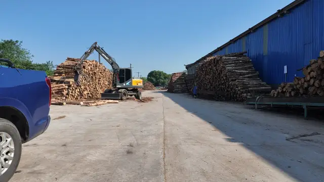 The customer’s log yard in Sichuan, with a grapple loader and stacked logs